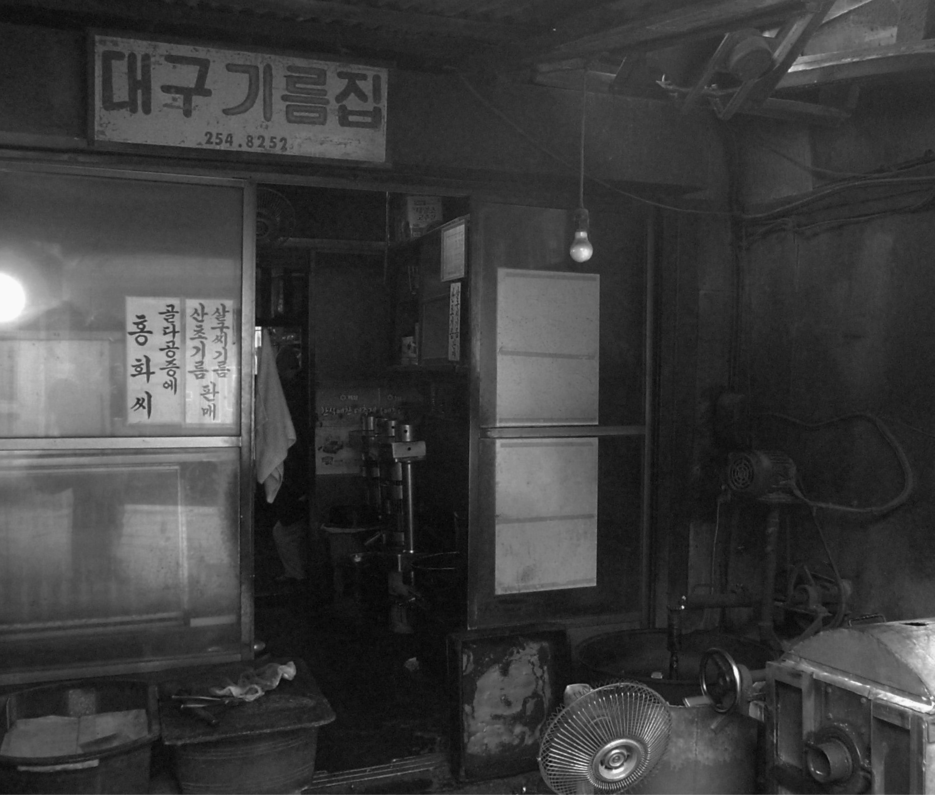 1972年の韓国の伝統的な小さな油屋の外観。看板に「大邱機油集」と書かれており、窓に韓国語の看板が表示されている